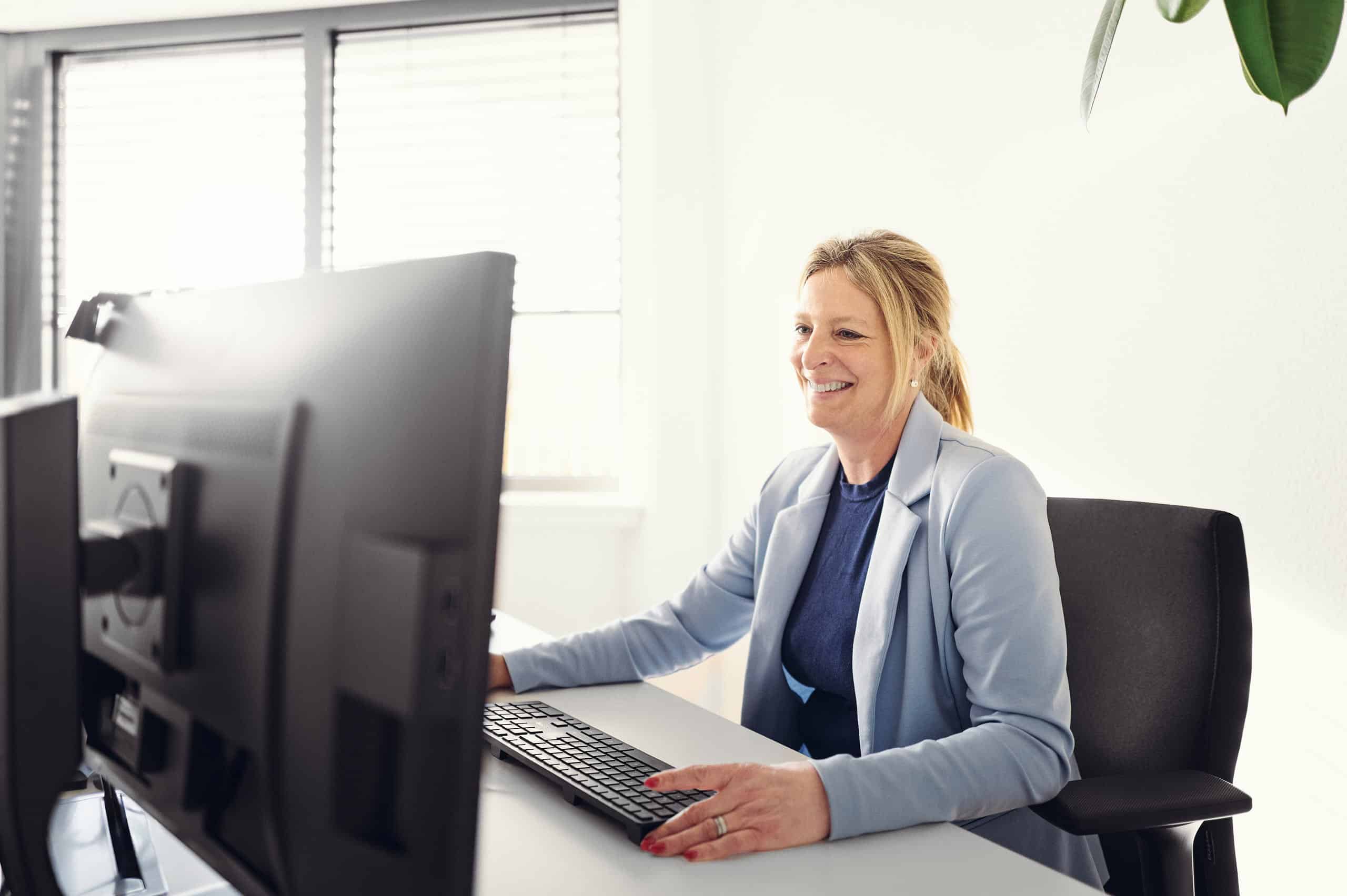Christel Heusler est assise devant son ordinateur, le sourire aux lèvres, et travaille.