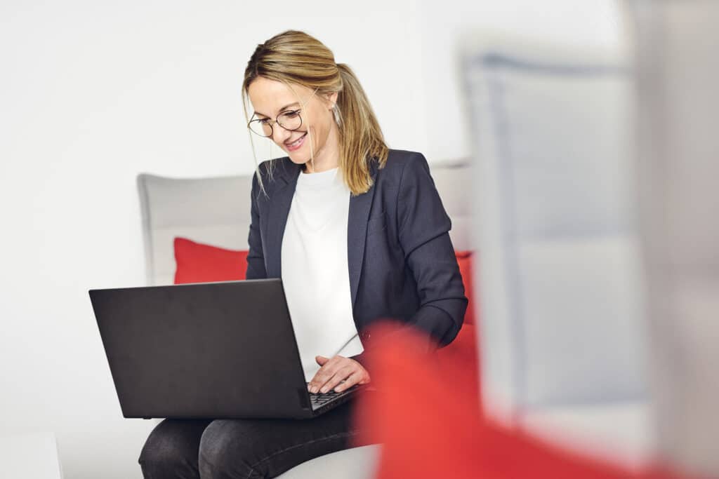 Celine Spitz travaille sur son ordinateur portable, assise sur le canapé du salon kwsoft.