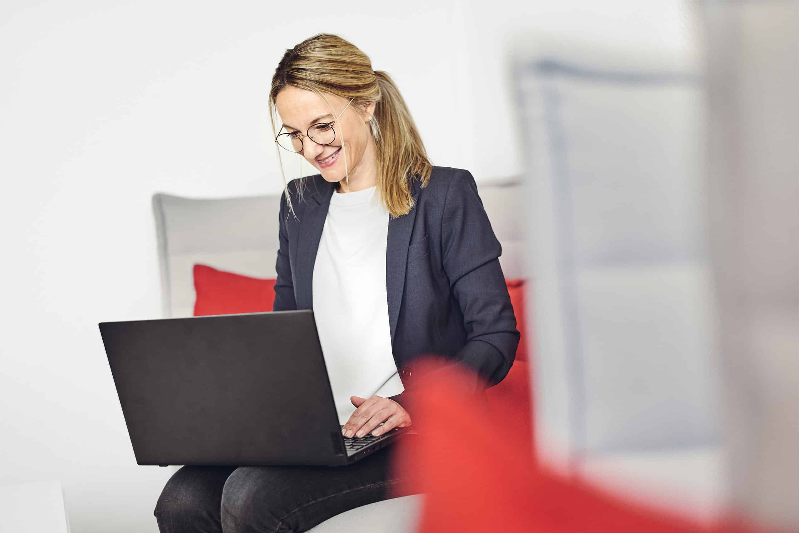 Celine Spitz travaille sur son ordinateur portable, assise sur le canapé du salon kwsoft.
