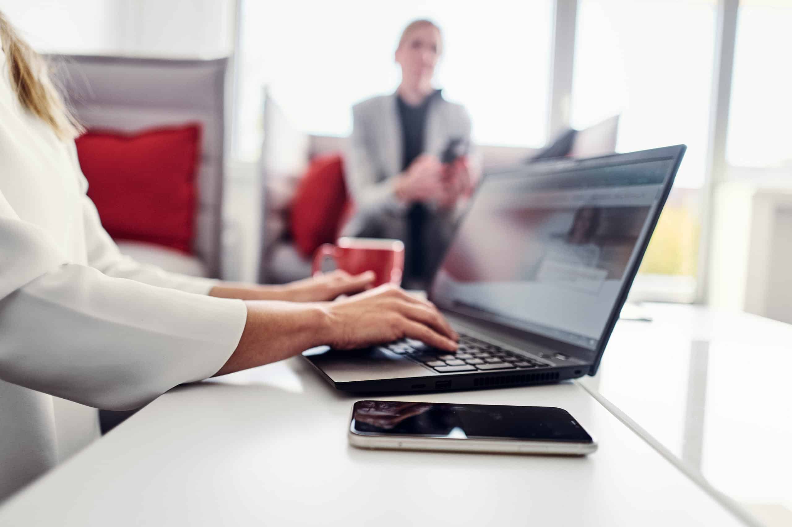 Une personne est assise sur le canapé du salon kwsoft et consulte le site web de Kwsoft sur son ordinateur portable.