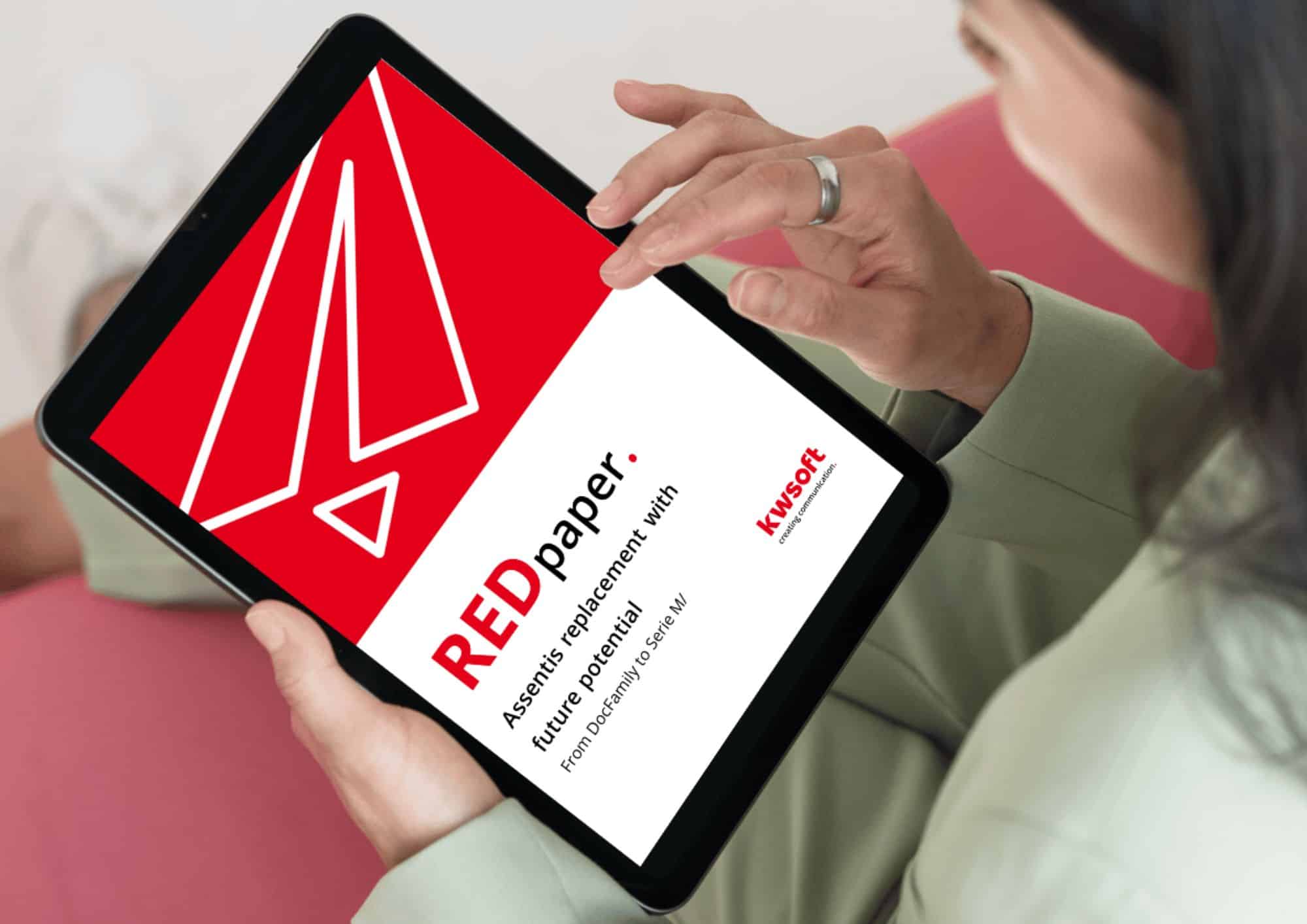 L'image montre une tablette tenue par quelqu'un qui affiche la couverture du REDpaper « Assentis Replacement ».