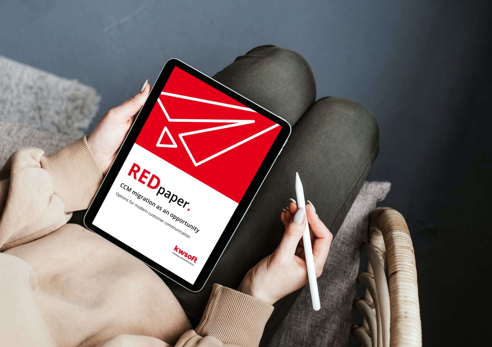 L'image montre une tablette tenue par quelqu'un qui affiche la couverture du REDpaper « CCM – Migration ».