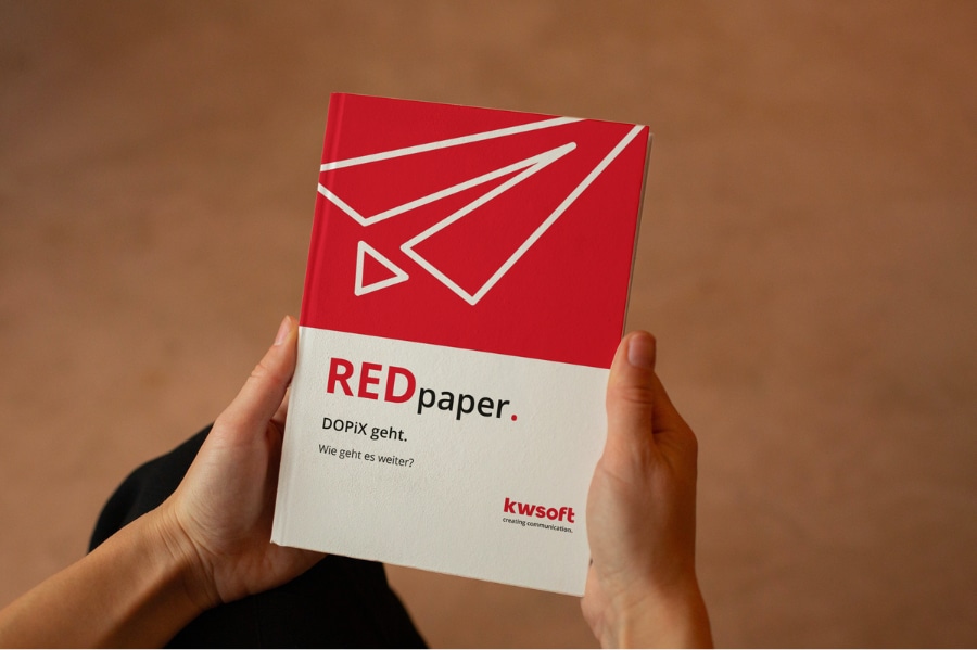 L'image montre une personne tenant le document REDpaper sur le remplacement de « DOPiX ».